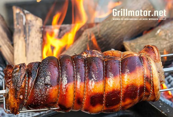 Grillmotor Landmann beim grillen eines Schweinebratens über dem offenen Feuer