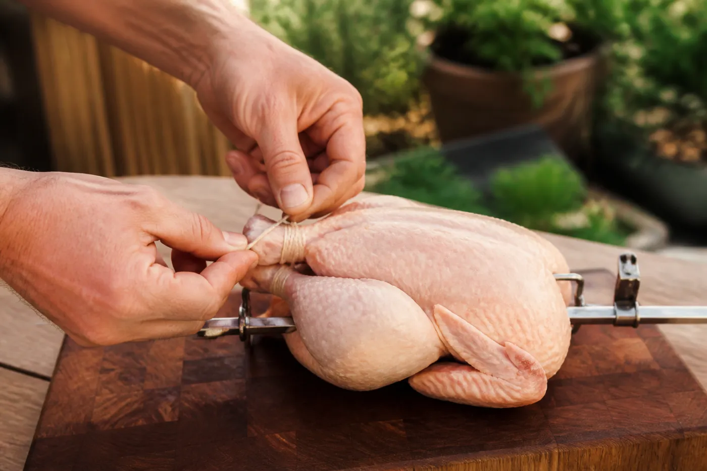 Flügel und Keulen des Hähnchens werden mit Küchengarn angebunden